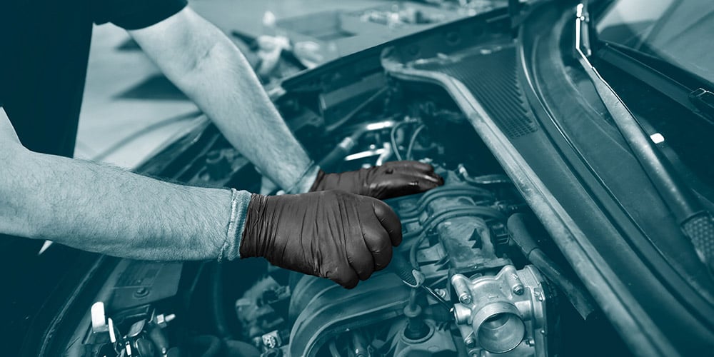 Mechanic wearing black nitrile gloves to repair a car engine made by Unigloves