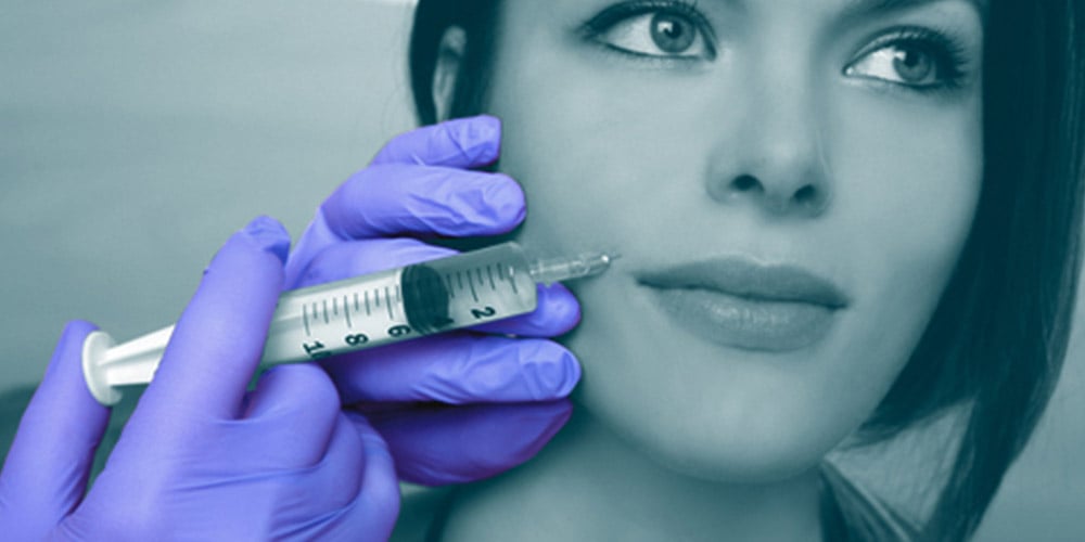 A medical professional administering a cosmetic surgery injection wearing Unigloves nitrile gloves.